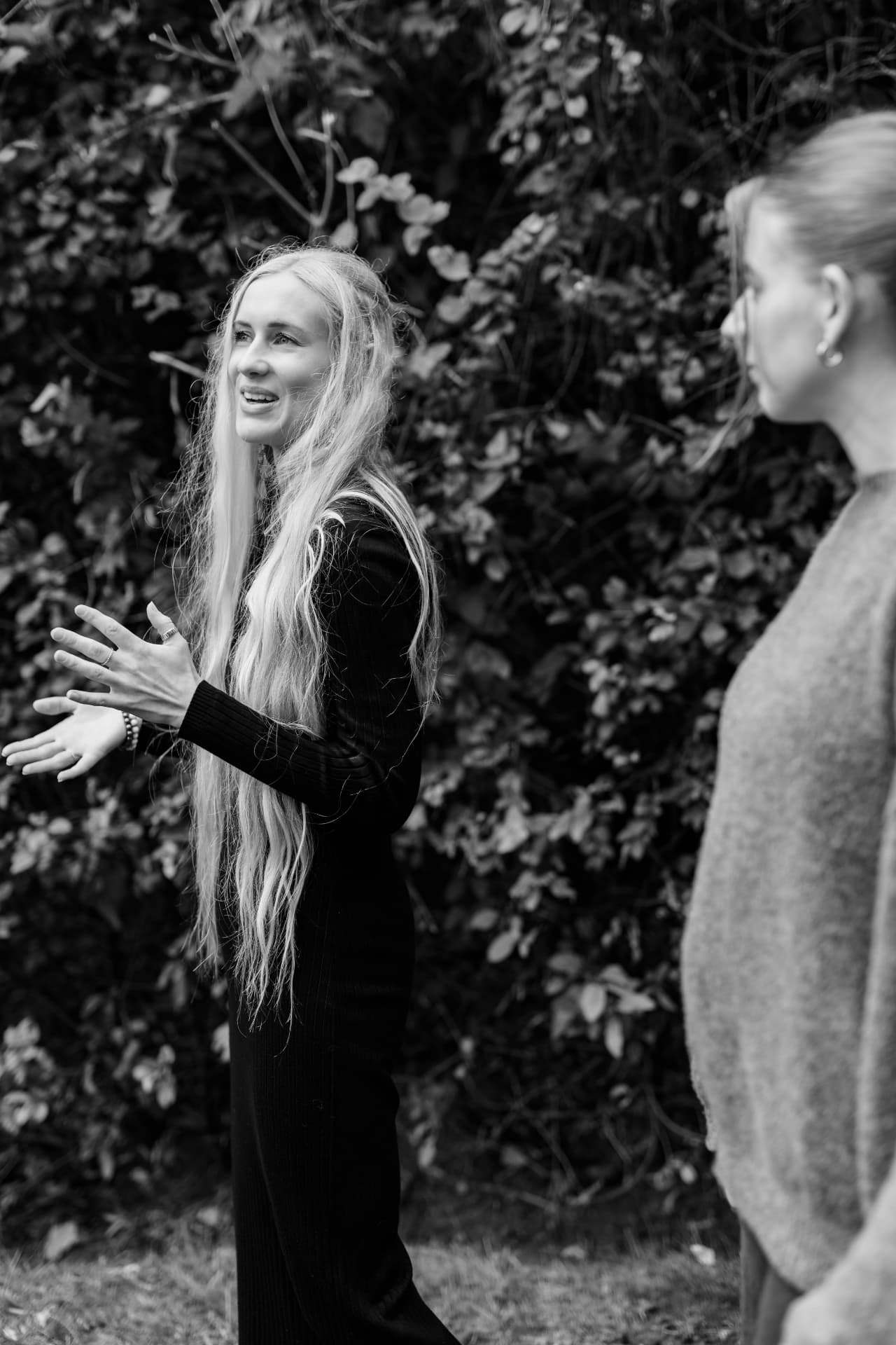 Sarah in conversation outdoors, in black and white
